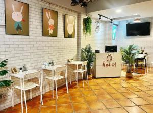 a restaurant with white tables and chairs and a tv at Tourist Bunny Hostel in Tamsui