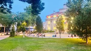 a group of people sitting in a park in front of a building at Escapist Apartments in Niš