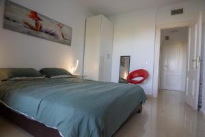 a bedroom with a bed and a red chair at appartement gelegen aan de golfbaan op La Quinta Benahavis Marbella in Benahavís