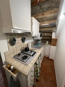 a kitchen with white cabinets and a stove top oven at Casetta Marilà in Lucignano +6 photos