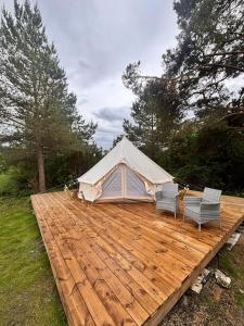 a tent sitting on a wooden deck with two chairs at Anniksson Glamping Telk- Loodustelk in Virtsu