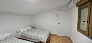 a white room with two beds and a window at Atico CabezoDoce in Calahorra
