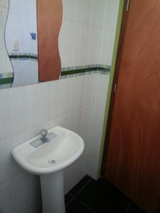 a bathroom with a white sink and a mirror at Hostal Arcangel in Abancay