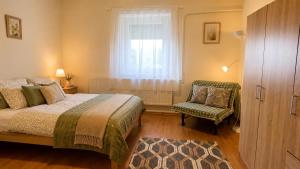 a bedroom with a bed and a chair and a window at Zöld Vendégház in Csernely