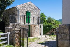 a stone house with a green door and a balcony at Kuca za odmor Kornic in Kornić