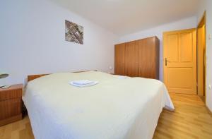 a bedroom with a white bed and a wooden floor at Kuca za odmor Kornic in Kornić