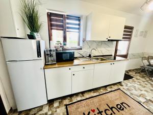 a kitchen with white cabinets and a white refrigerator at S-HOUSE Avrig , Apartament cu Aer Condiționat, 2 Dormitoare, Bucatarie, Terasa , Curte Privată Parcare Gratuită in Avrig