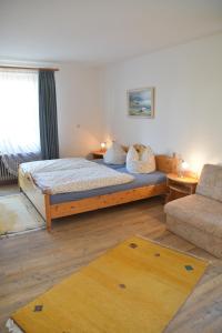 a bedroom with a bed and a couch and a rug at Landhaus Lena in Schönwald