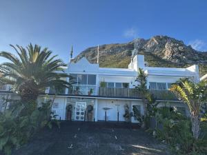 a white house with a mountain in the background at 78on5th in Hermanus in Hermanus