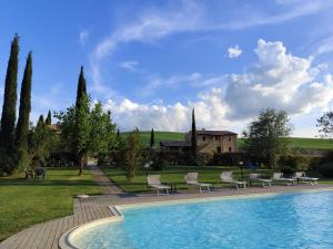 a swimming pool with chairs and a house in the background at Agriturismo Marinello in Pienza