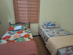 a bedroom with two beds and a window at Jeda Salihah in Baling