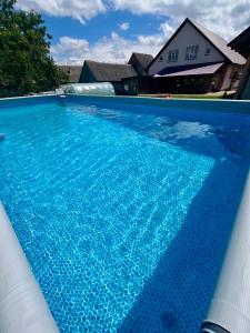a swimming pool with blue water in front of a house at У Лариси in Solochyn