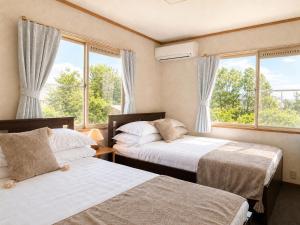 two beds in a room with two windows at Biwa 広々テラス bbq 無料駐車場 湖まで徒歩3分 in Takashima