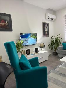 a living room with a blue chair and a tv at Apartman DIN in Travnik