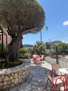 a patio with tables and chairs and a tree at Hotel Nostos in Nydri