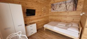 ein kleines Schlafzimmer mit einem Bett und einem Fernseher in der Unterkunft Gemini MiniDomki in Ustka