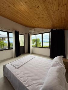 a bedroom with a large white bed with windows at Perseku GuestHouse in Shirokë
