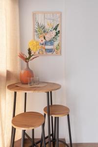 a table and two stools with a vase and a painting at Emarooms Boutique Laredo in Laredo