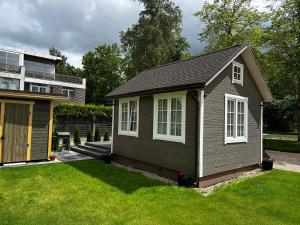 a small house in a yard next to a building at Melluži tiny house 35m2 in Jūrmala +11 photos