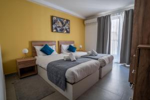 a bedroom with two beds with blue pillows at Stillel Retreat Suites in St. Paul's Bay