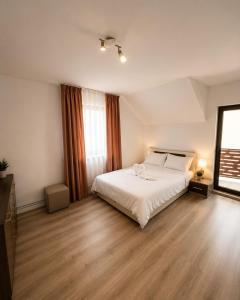 a bedroom with a white bed and a wooden floor at Casa Casy in Oradea +34 photos