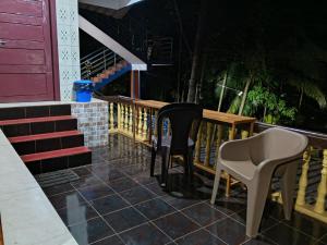a porch with two chairs and a table and stairs at Eden Homes in Honāvar +18 photos