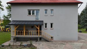 a white house with a porch and a balcony at Maziarówka in Basznia Dolna