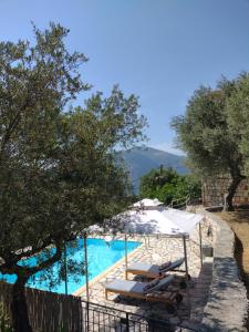 a swimming pool with a white umbrella and lounge chairs at IthakiHouse II in Vathi