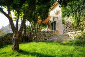 a stone house with a stone wall and a tree at Lues Incanto in Ragusa
