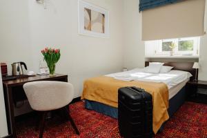a hotel room with a bed and a desk and a suitcase at B&B Wieniawa in Leszno