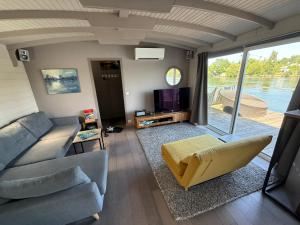 a living room with a couch and a tv at Maison bord de Seine à 20 min de Paris in Villennes-sur-Seine
