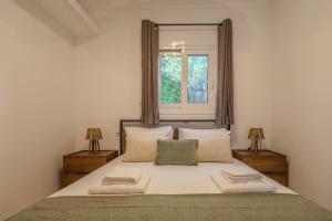 a bedroom with a large white bed with a window at San House 1 in Archangelos