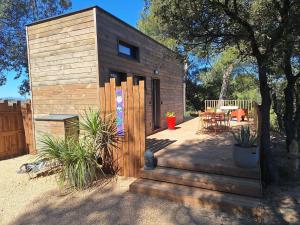 a small wooden cabin with a wooden staircase in a yard at Tiny House L'esquirou in Pourrières