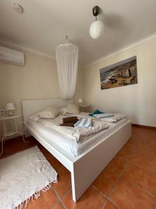 a bedroom with a white bed with a chandelier at Poolvilla Casa Sol in Aljezur +29 photos
