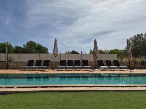a swimming pool with lounge chairs and umbrellas at YourHouse Sa Riba Villa in Son Carrió