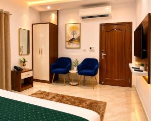 a hotel room with a bed and two chairs and a door at The Hotel Atlantis Suites Sigra Road Near Vishwanath Temple in Varanasi