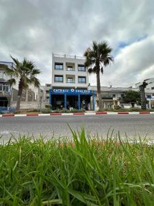 a building with palm trees in front of a street at Catrass Oualidia Apartments in Oualidia