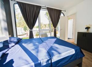 a bedroom with a blue bed and a large window at EloA Glamping in Petrovac na Moru