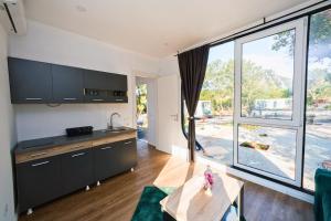 a kitchen with black cabinets and a large window at EloA Glamping in Petrovac na Moru