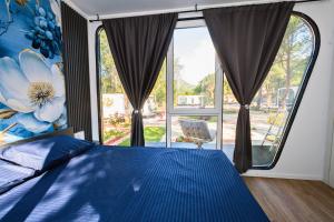 a bedroom with a blue bed and a large window at EloA Glamping in Petrovac na Moru +13 photos