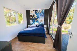 a bedroom with a bed with blue sheets and a window at EloA Glamping in Petrovac na Moru