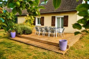 a wooden deck with chairs and a table on it at Le Cercle des Éléments - Maison d'exception - Cinéma, Parking privé -Classé 4 étoiles in La Rivière-de-Corps