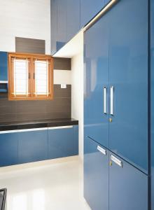 a kitchen with blue cabinets and a glass door at Meadows Homestay in Madurai