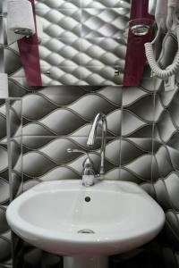 a sink in a bathroom with a black and white tiled wall at Hotel Heimli in Prishtinë +40 photos