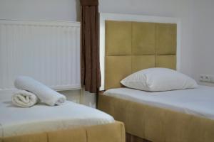 a bedroom with two beds and a headboard with towels at Hotel Heimli in Prishtinë