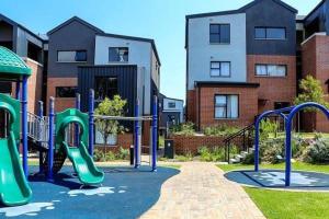 a playground with a slide in a yard with buildings at Luxury Apartment - Breathtaking River Views in Kyalami