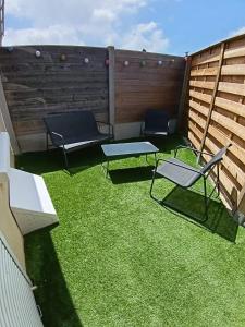 a patio with two chairs and a bench on the grass at La parenthèse Audomaroise in Heuringhem