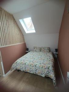 a bedroom with a bed with a comforter and a window at La parenthèse Audomaroise in Heuringhem