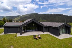 a black house with two people sitting on the grass at Chalet Rila in Govedartsi