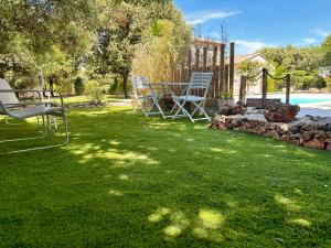 a yard with two chairs and a table in the grass at Hébergement standing au calme in Saint-Maximin-la-Sainte-Baume